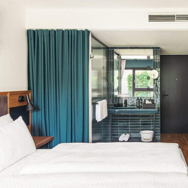Doppelbett neben einem Badezimmer, das mit einem grünen Vorhang verschlossen werden kann