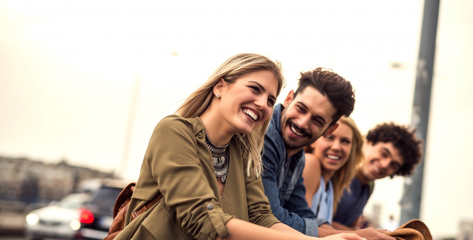 Four people in a row laugh at each other 