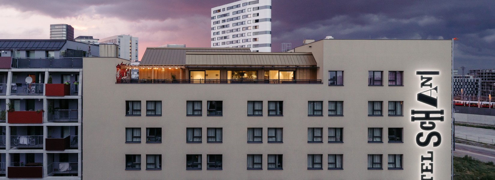 House facade of the Hotel Schani Wien with view of the Rooftop Event Space at dusk 