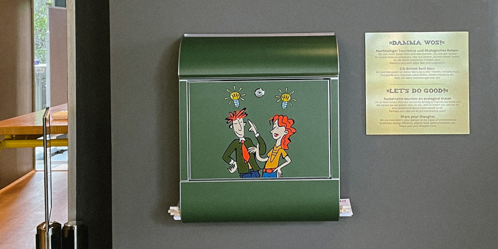 Grüner Briefkasten neben einer goldenen Tafel an einer grauen Wand