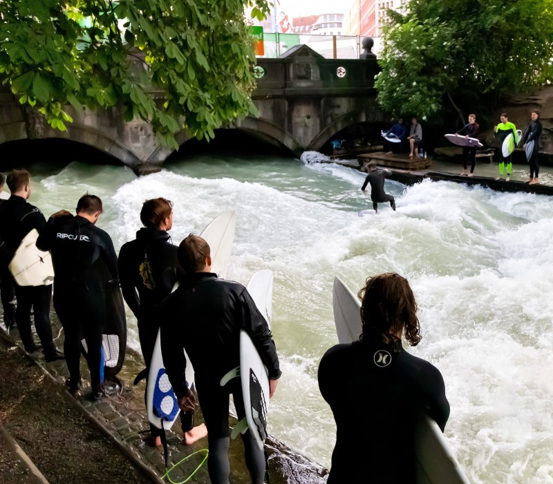 Surfer on the Eisbach wave with spectators in Munich