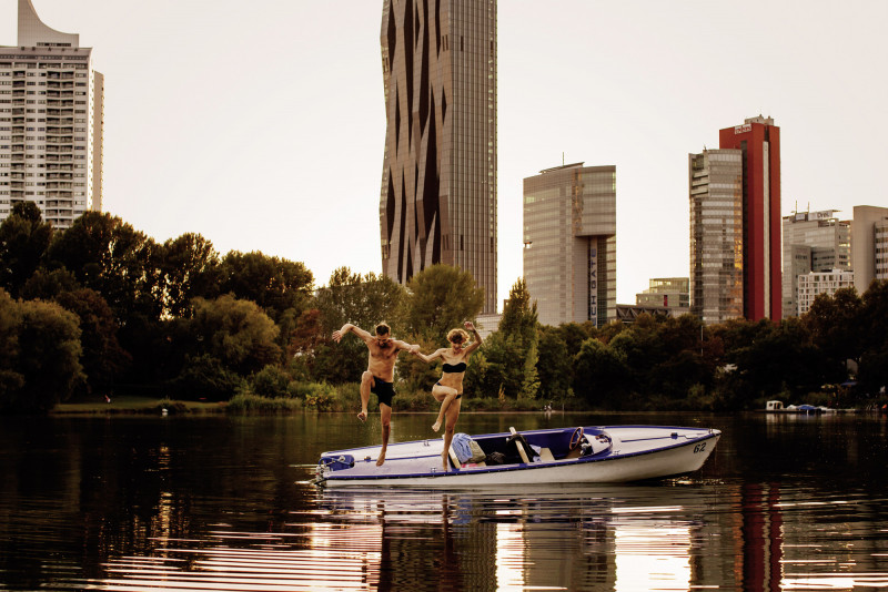 Zwei Personen springen von einem Boot in die Alte Donau in Wien