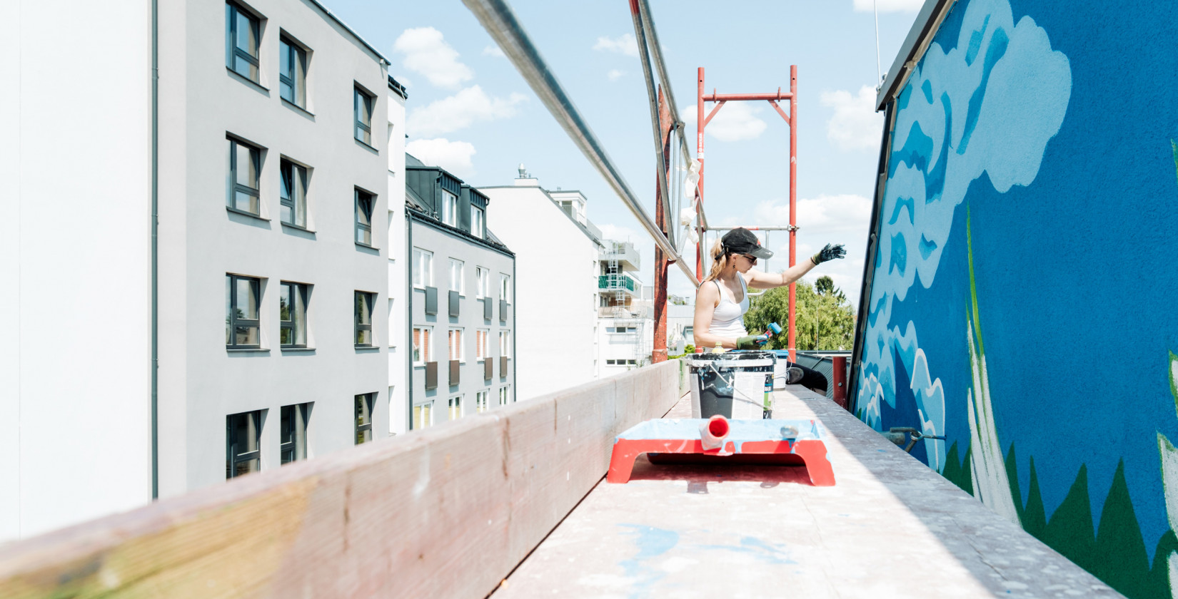 Eine Frau auf einem Gerüst arbeitet an einem Grafitti