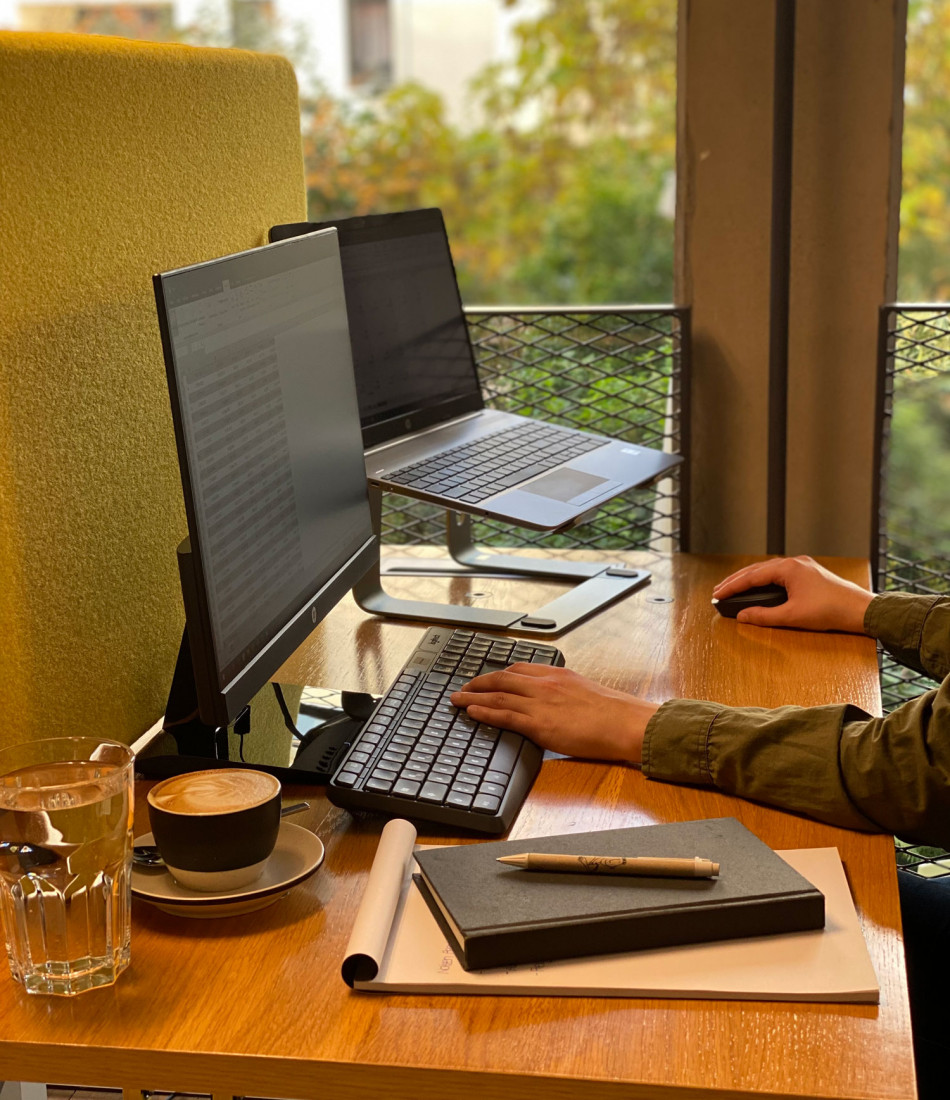 Nahaufnahme von einem Arbeitsplatz mit einem Laptop, Bildschirm und einer Tasse Kaffee
