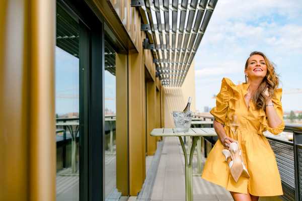 Smiling woman in yellow dress on terrace in Schani's Rooftop