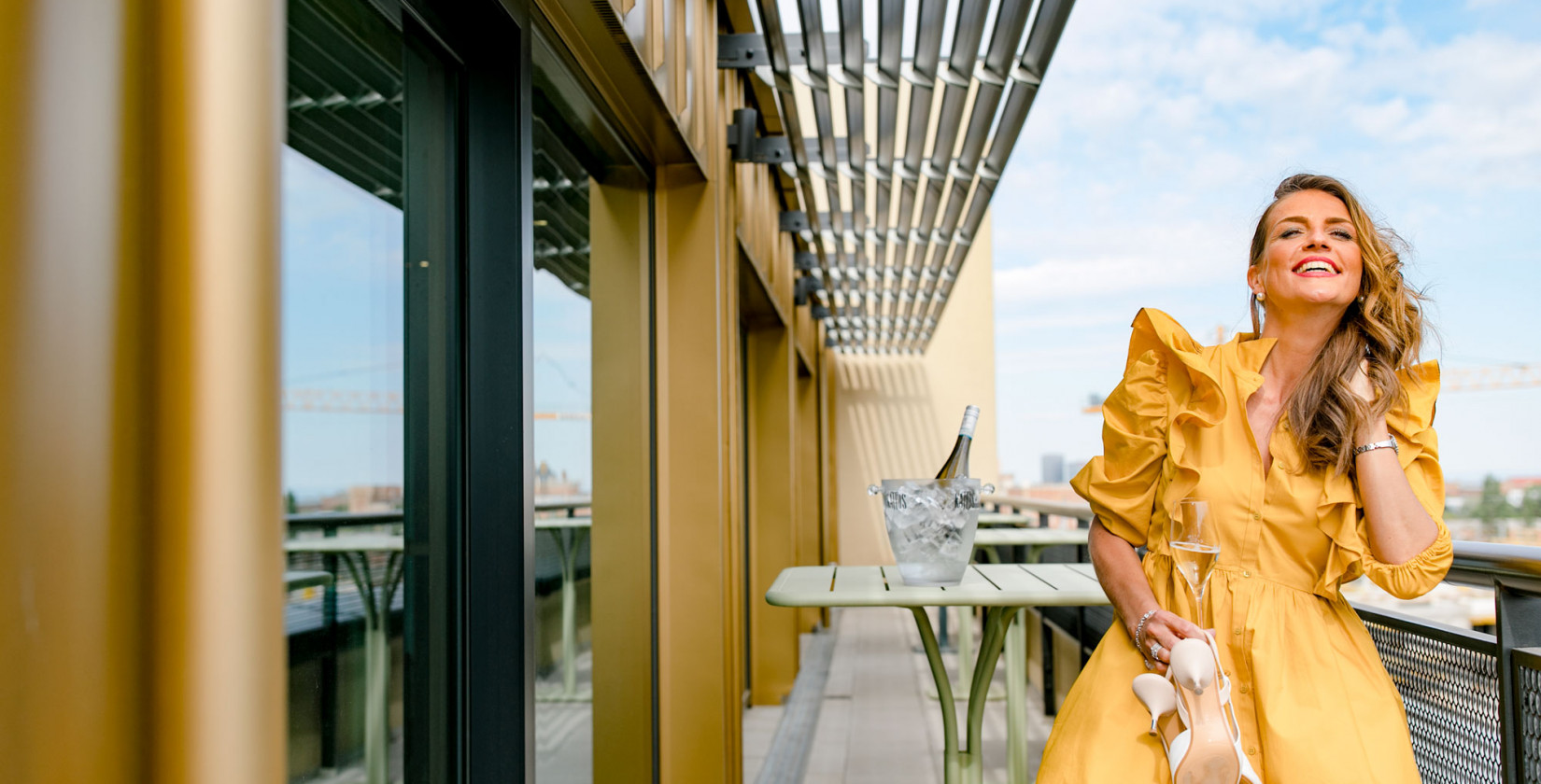 Woman in a yellow dress drinking champagne on the rooftop eventspace