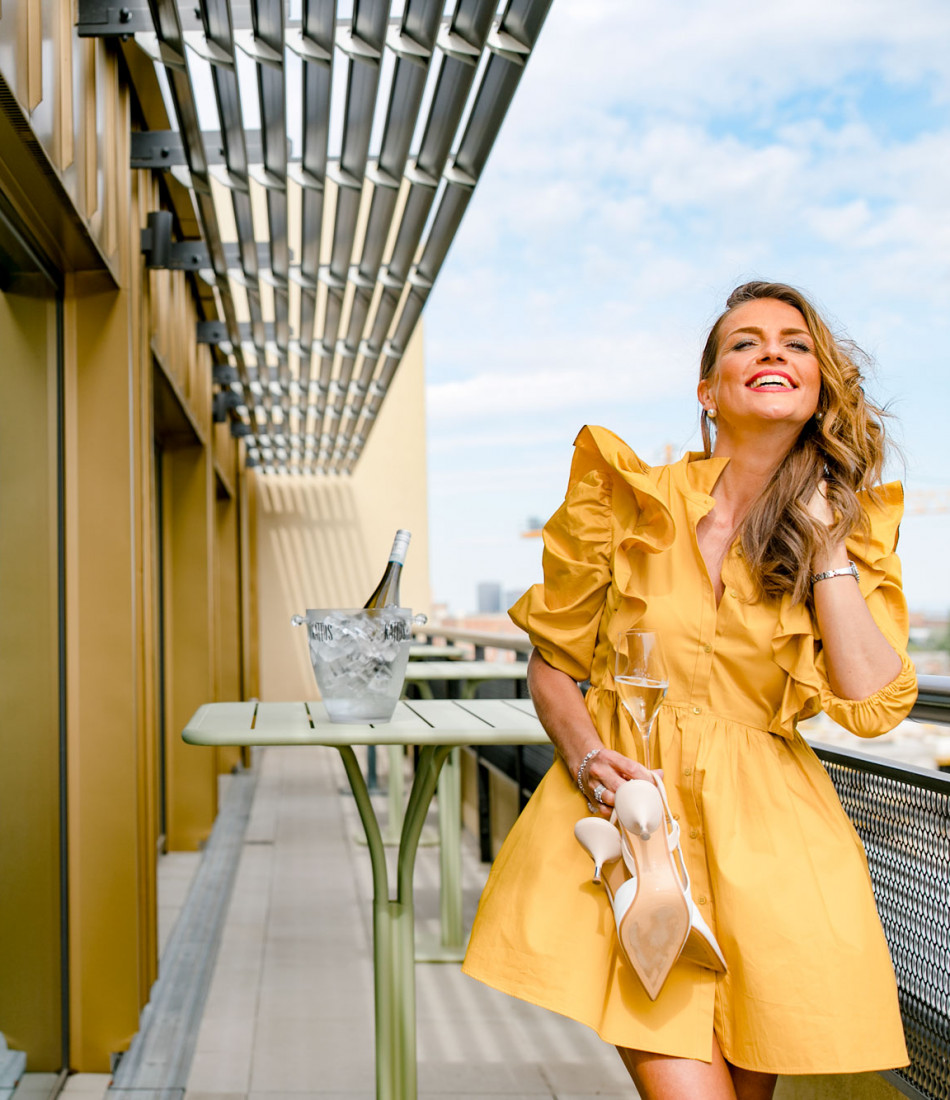 Smiling woman in yellow dress on terrace in Schani's Rooftop