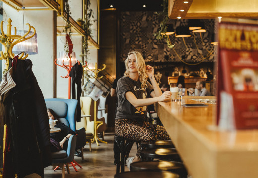 Frau sitzt an der Schani's Bar und trinkt Kaffee