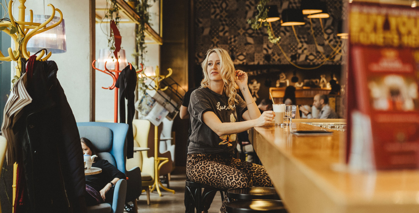Frau sitzt mit Kaffee an Schani's Bar