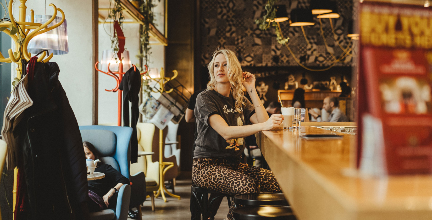Dame sitzt an Schani's Bar mit einem Kaffee