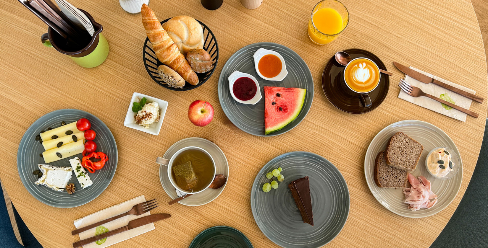 Frühstückstisch mit Gebäck, Käse, Obst, Kaffee, Tee und Saft