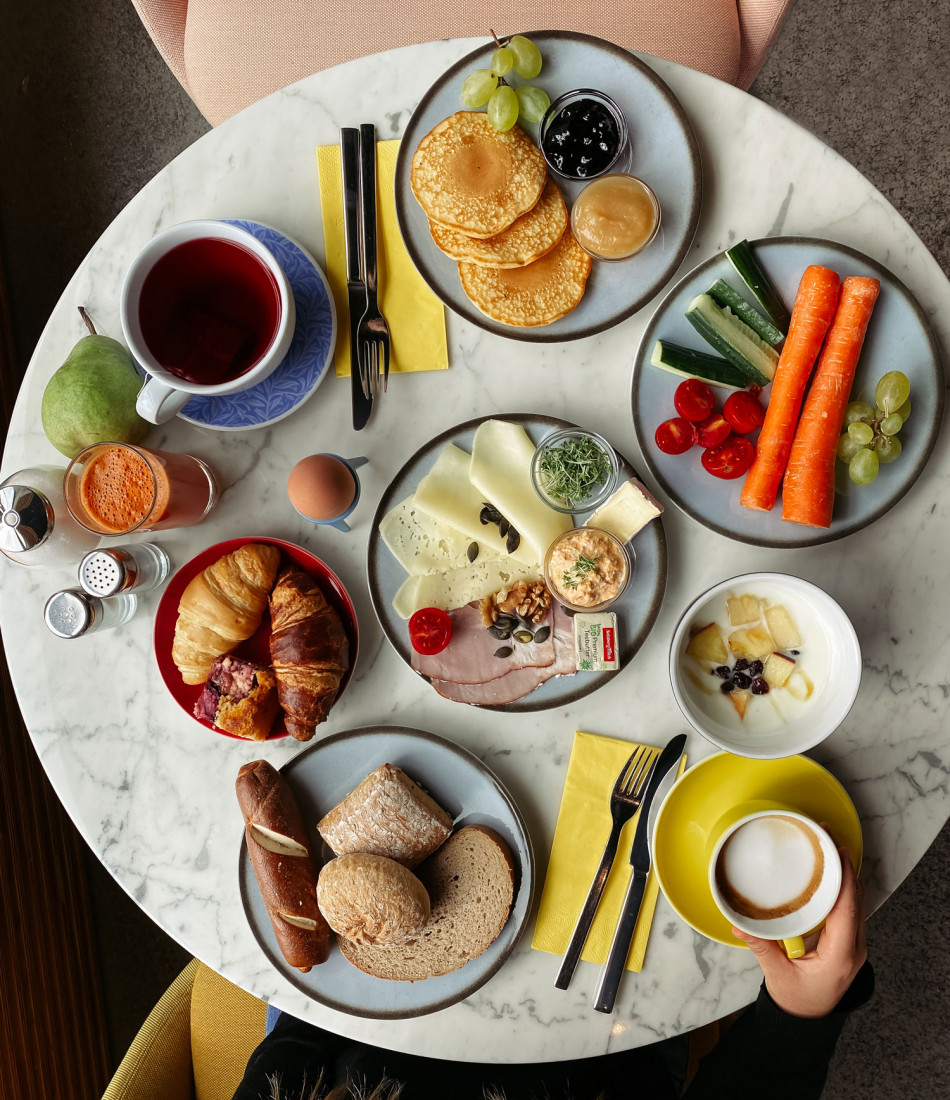 Ein Frühstückstisch mit Gebäck, Gemüse, Kaffee, Obst und Pancakes