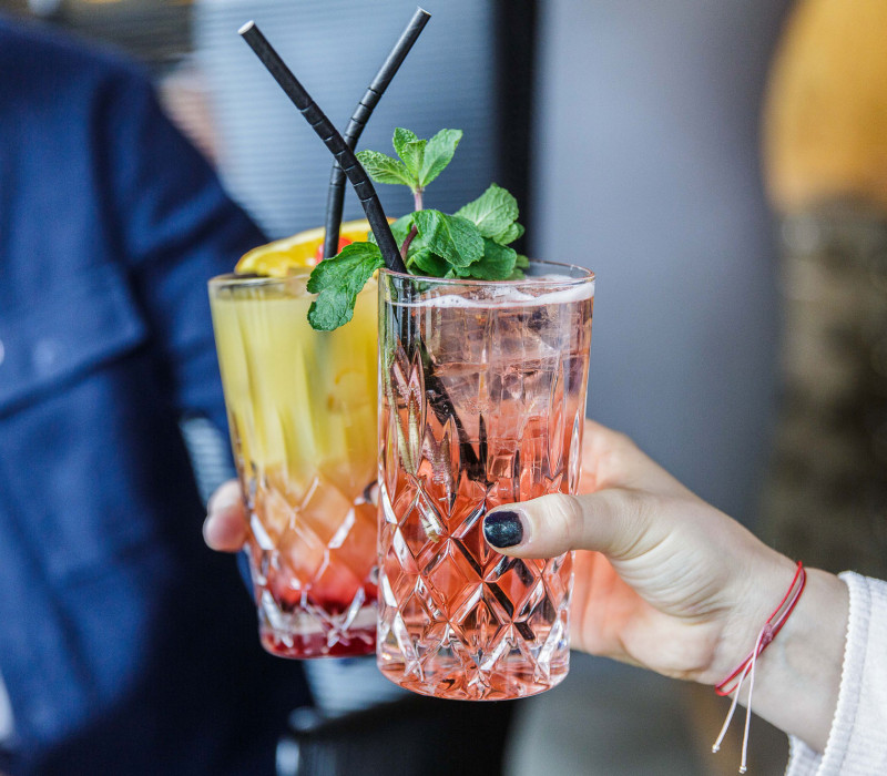 Zwei Personen stoßen mit Getränken in Longdrink Gläsern an