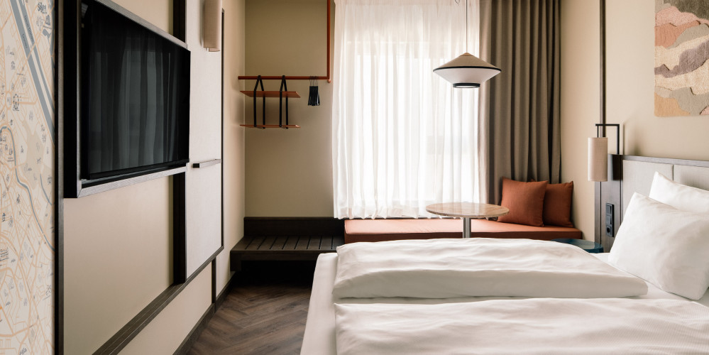 Doppelbett, Fernseher, Fensterbank und Hutablage in einem koscher-friendly Hotelzimmer in Wien