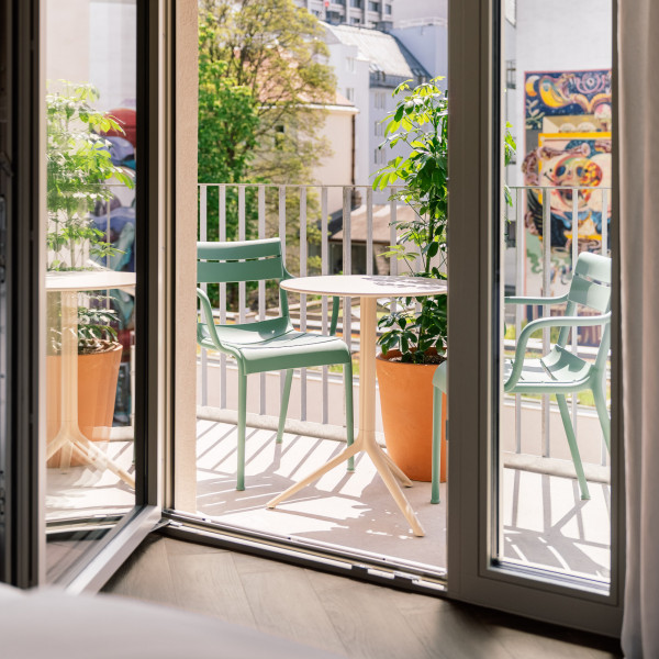 Blick vom Bett auf den Balkon in einem Zimmer im Hotel Schani City