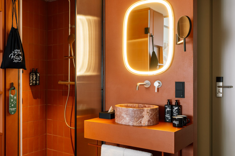 Badezimmer mit Waschtisch, Regendusche, Kosmetik und Föhn in einem Hotelzimmer