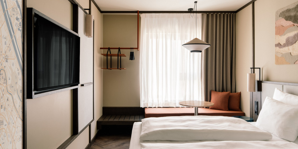Doppelbett, TV und Fensterbank in einem Zimmer im Hotel Schani City