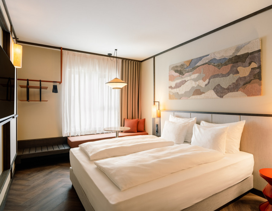 Bed, window seat and TV in a room at Hotel Schani City