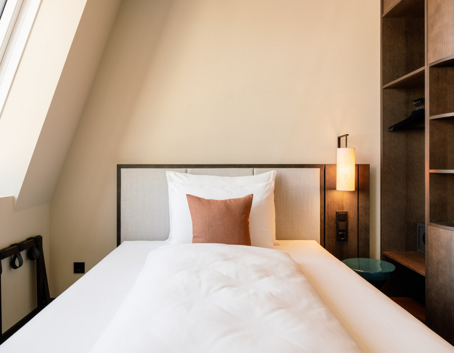 Einzelbett und Ablageflächen in einem Einzelzimmer im Hotel Schani City