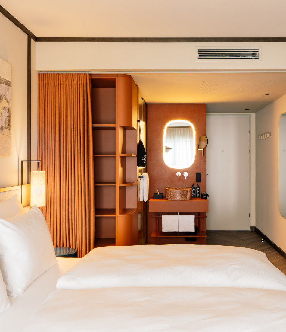Hotelzimmer mit Doppelbett, offenem Bad und Ablageflächen