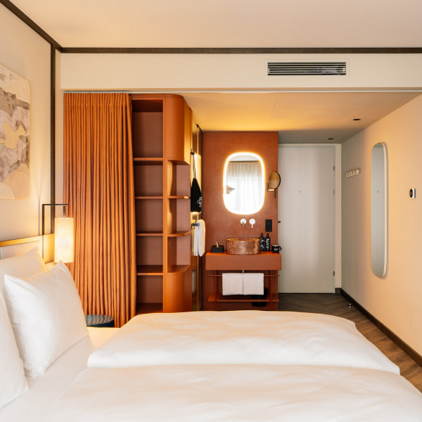 Hotelzimmer mit Doppelbett, offenem Bad und Ablageflächen