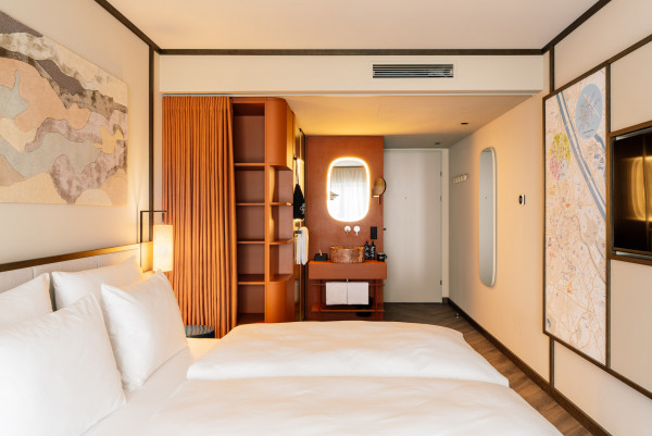 Doppelbett, Ablageflächen und offenes Badezimmer in einem Doppelzimmer im Hotel Schani City