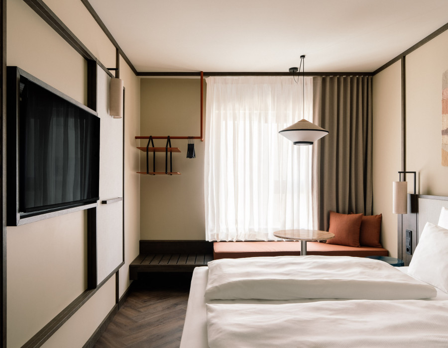 Double bed, TV and window seat in a hotel room for two guests