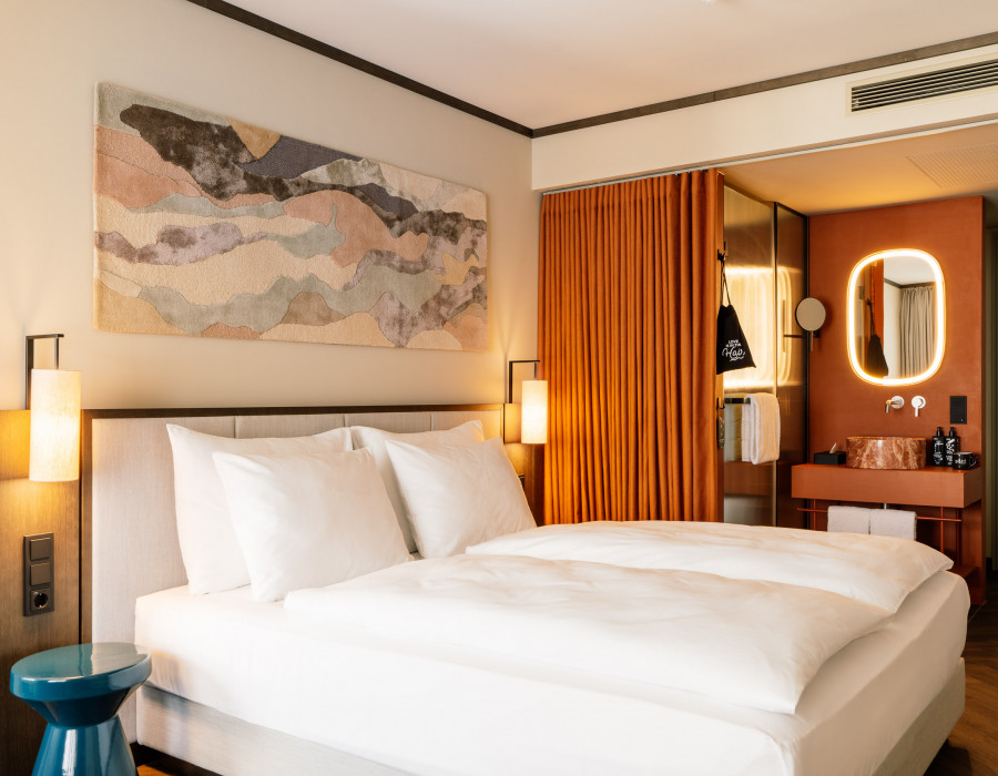 Double bed and open bathroom with a rainshower in a room at Hotel Schani City