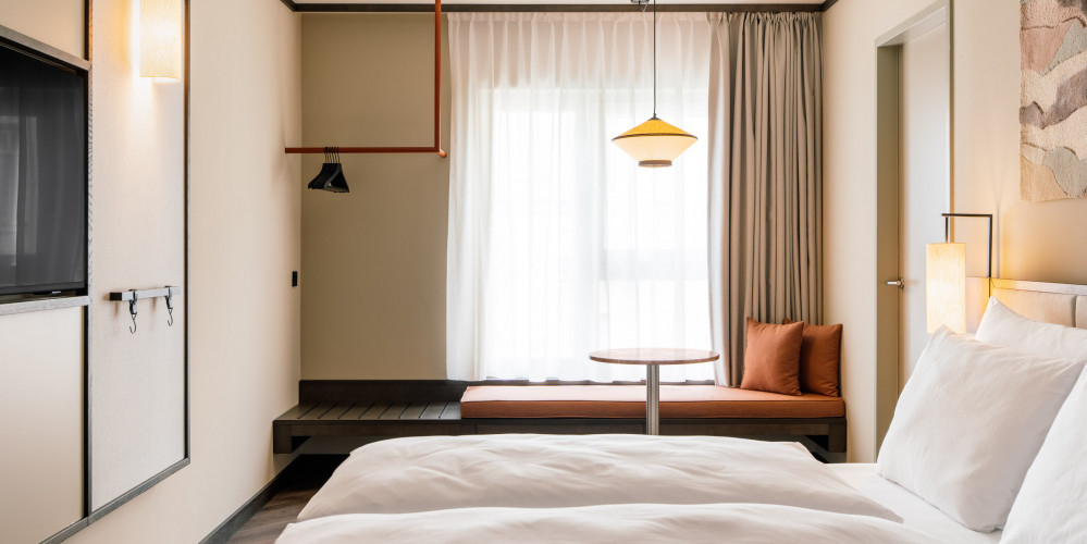 Double bed, TV and window seat in a hotel room for three guests