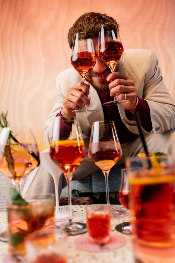 Ein Gast mit mehreren Gläsern in der Hand in der Vieami Rooftop Bar