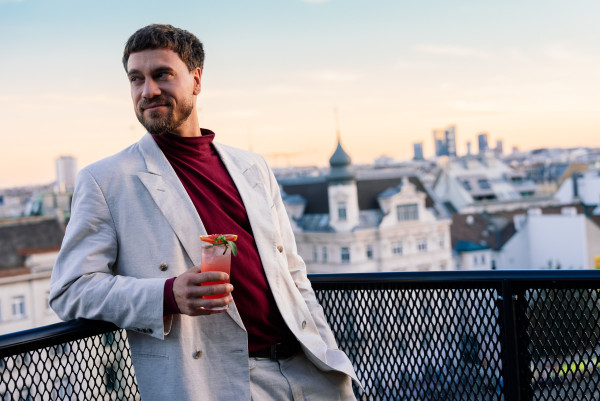 Ein Mann mit einem Drink in der Hand auf der Terrasse der Vieami Rooftop Bar