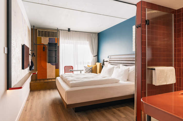 Fernseher, offener Kleiderschrank, Fensterbank und Doppelbett in einem Zimmer im Hotel Schani Naschmarkt 