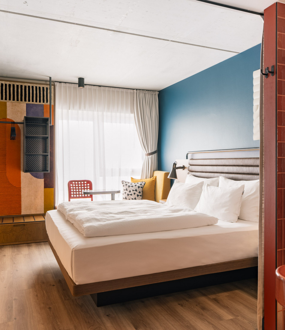 Helles Hotelzimmer mit einem Doppelbett und einer gepolsterten Fensterbank