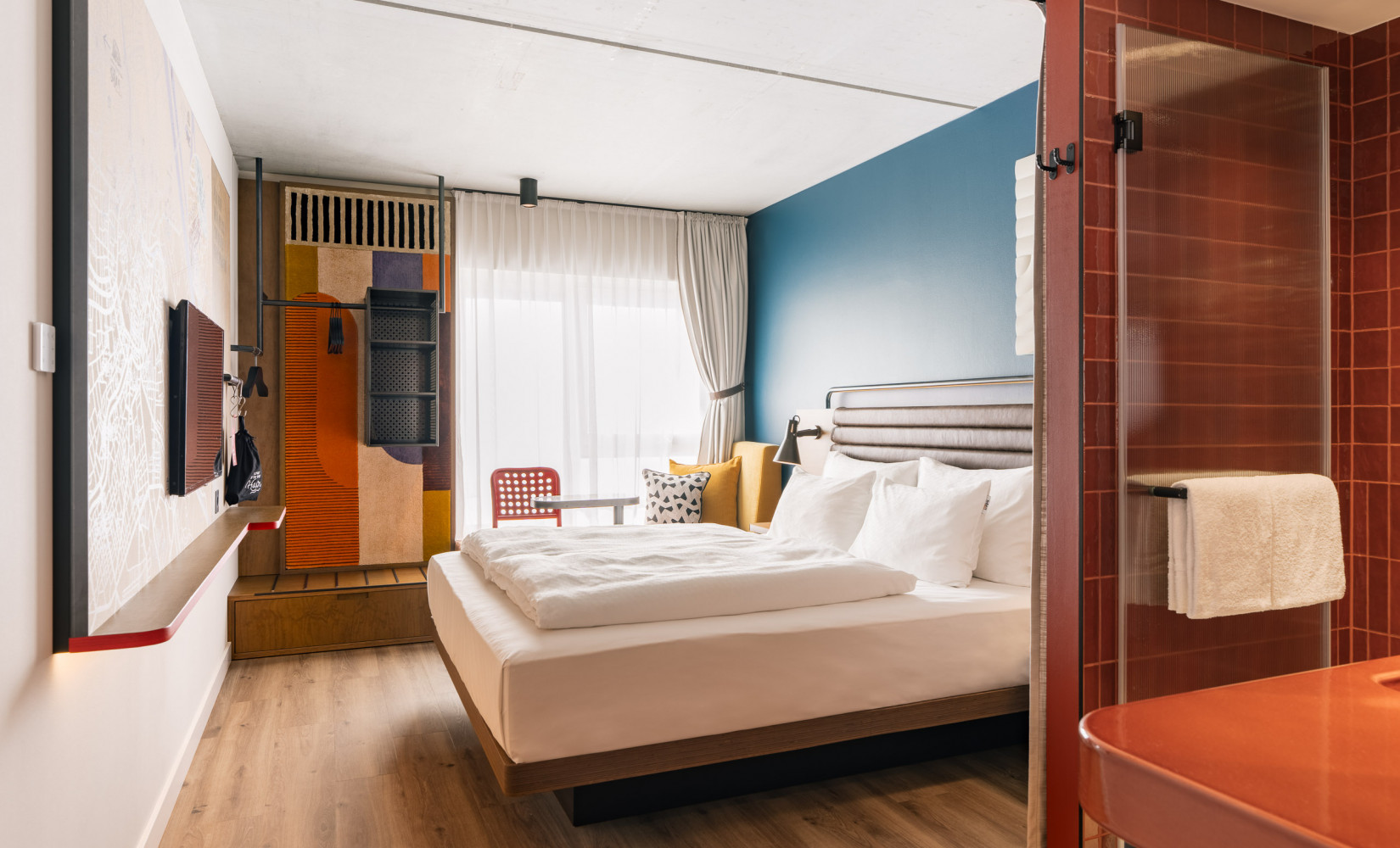 Helles Doppelzimmer mit einer Fensterbank und einem offenen Kleiderschrank im Hotel Schani Naschmarkt