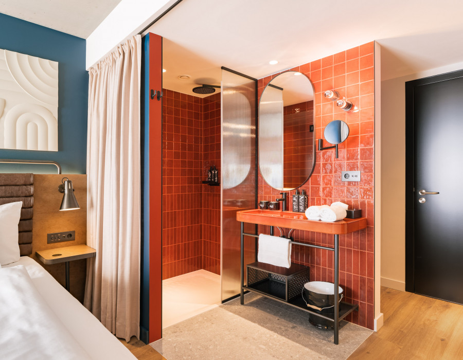 Offenes Badezimmer mit Regendusche, das durch einen Vorhang vom Zimmer getrennt werden kann