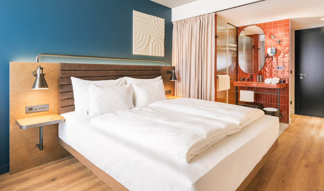 Bed next to an open bathroom in a room at Hotel Schani Naschmarkt