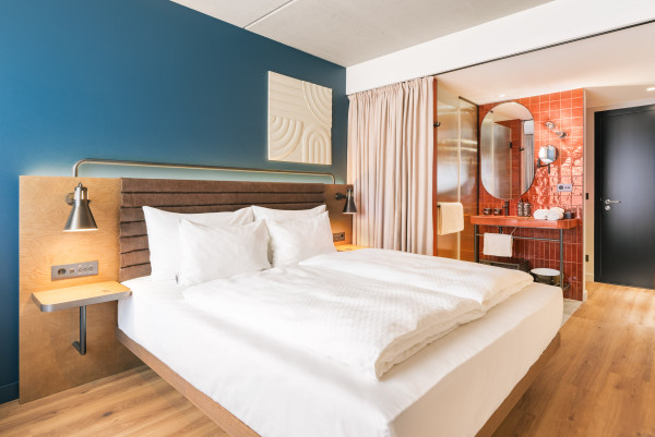 Bett und offenes Badezimmer im einem Doppelzimmer