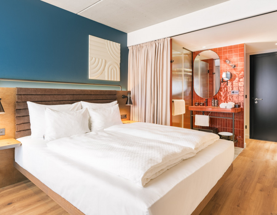 Doppelbett und offenes Badezimmer im Hotelzimmer beim Wiener Naschmarkt