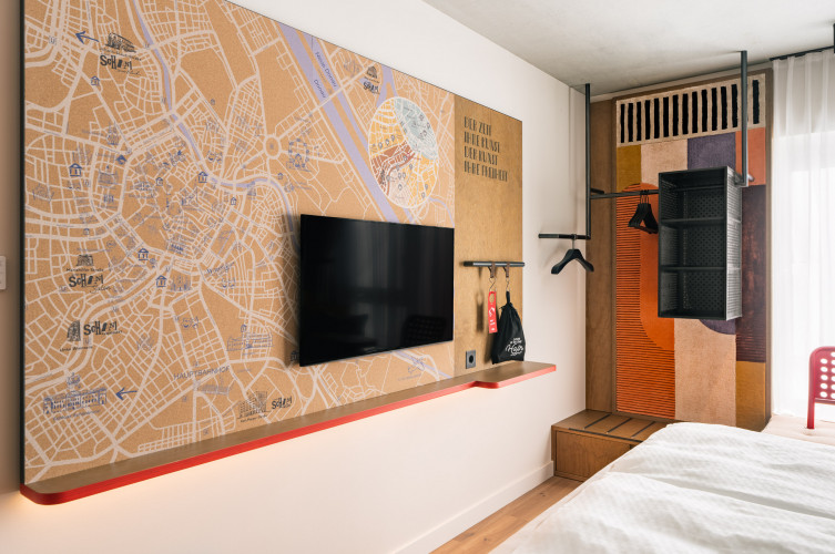 TV neben einem offenen Kleiderschrank in einem Zimmer im Hotel Schani Naschmarkt