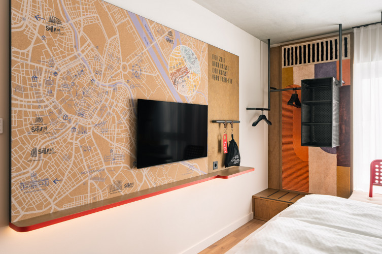 Stadtplan von Wien und Fernseher an einer Wand neben dem offenen Kleiderschrank im Hotel Schani Naschmarkt