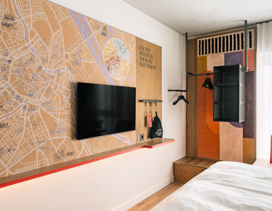 Offener Kleiderschrank, Fernseher und großer Stadtplan von Wien an einer Wand im Hotelzimmer