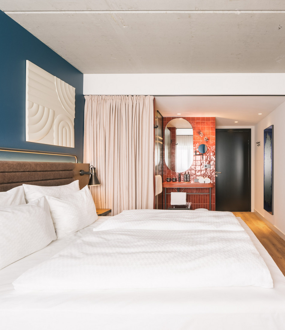 Doppelbett neben einem offenen Badezimmer im Hotel Schani Naschmarkt