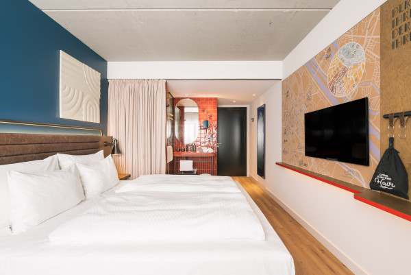 Bett, TV und offenes Badezimmer im Hotel Schani Naschmarkt