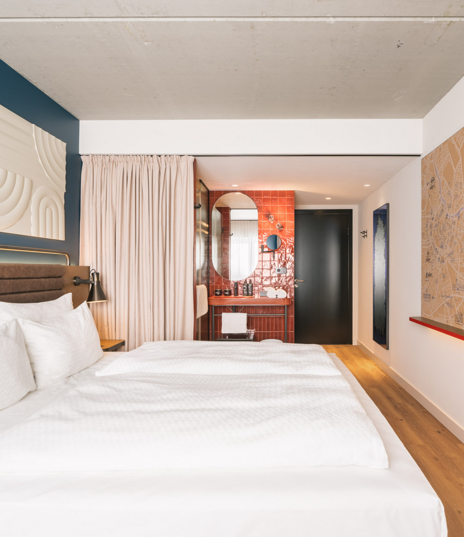 Doppelbett und ein Badezimmer mit Regendusche und Waschtisch im Hotel Schani Naschmarkt
