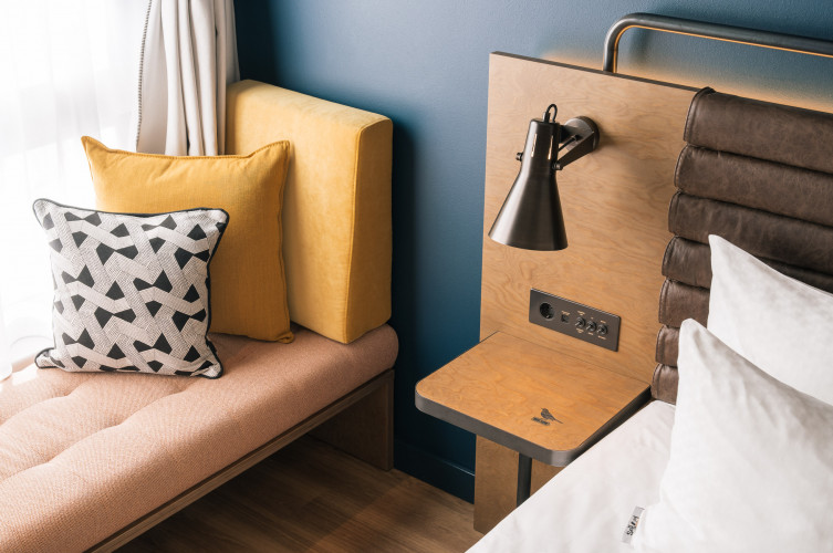 Kabellose Ladestation neben dem Doppelbett im Zimmer im Hotel Schani Naschmarkt