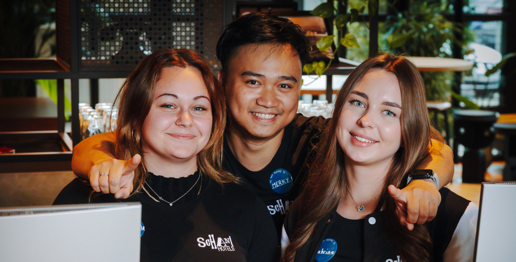 Drei Team-Mitglieder an der Rezeption lächeln