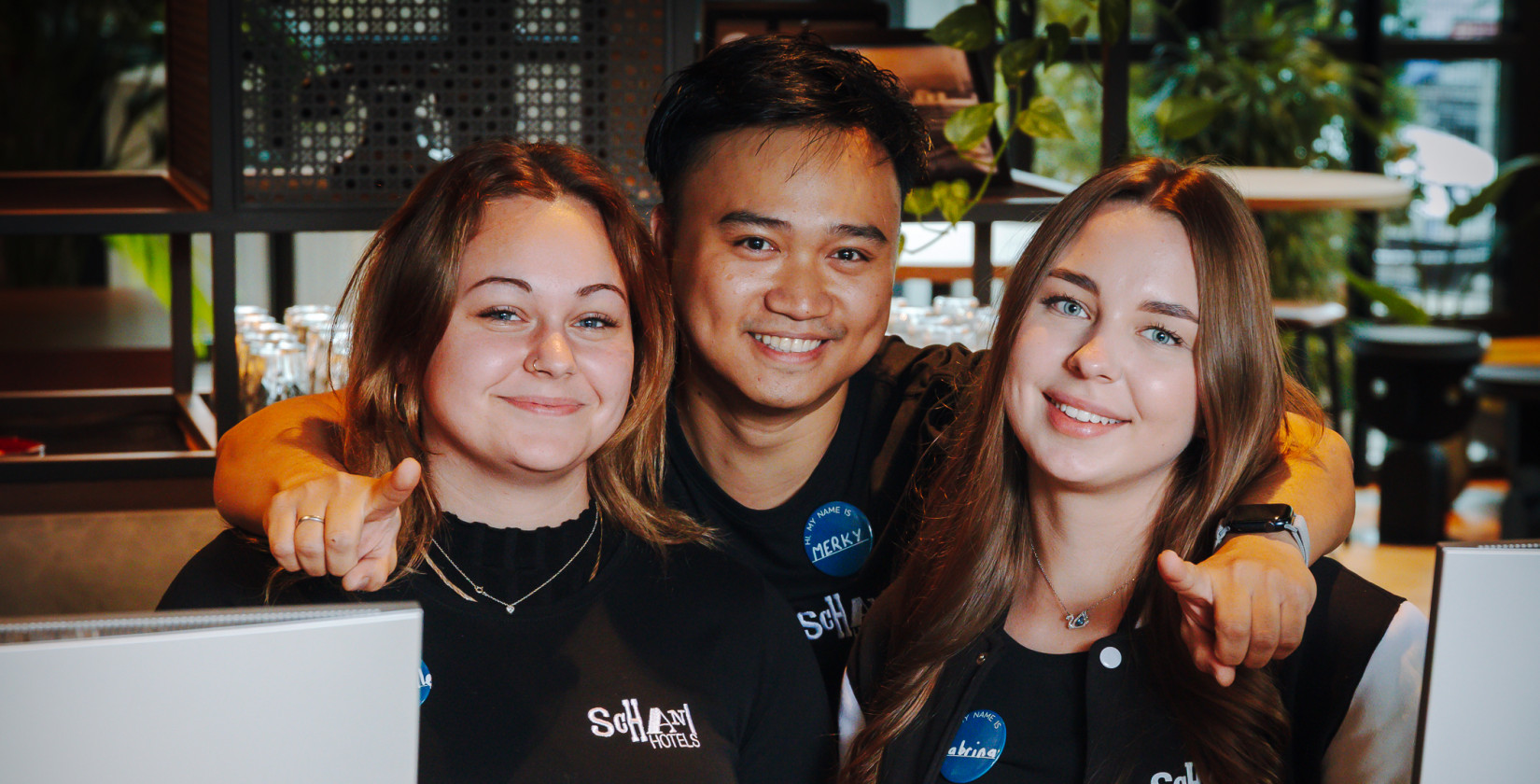 Drei lächelnde Mitglieder des Schani Teams an der Rezeption