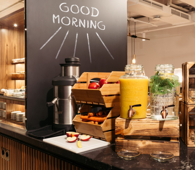 Saftpresse, frische Äpfel, Karotten und Orangensaft beim Frühstücksbuffet