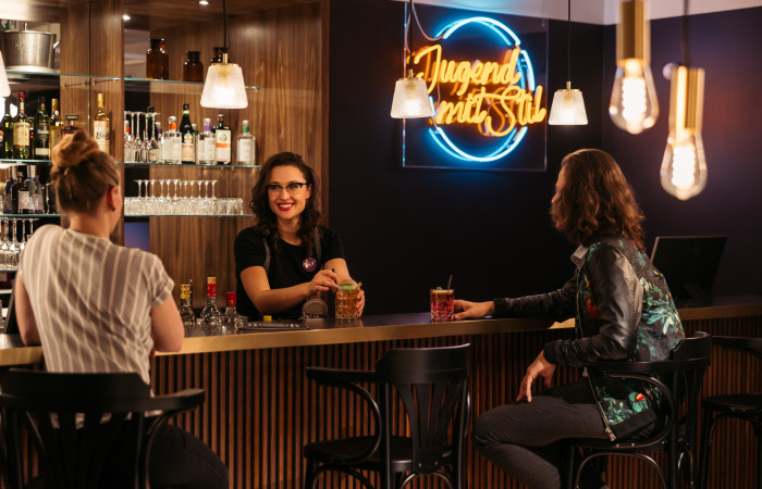 Zwei Frauen sitzen an der Bar des Hotels in der Mariahilferstraße und trinken Cocktails