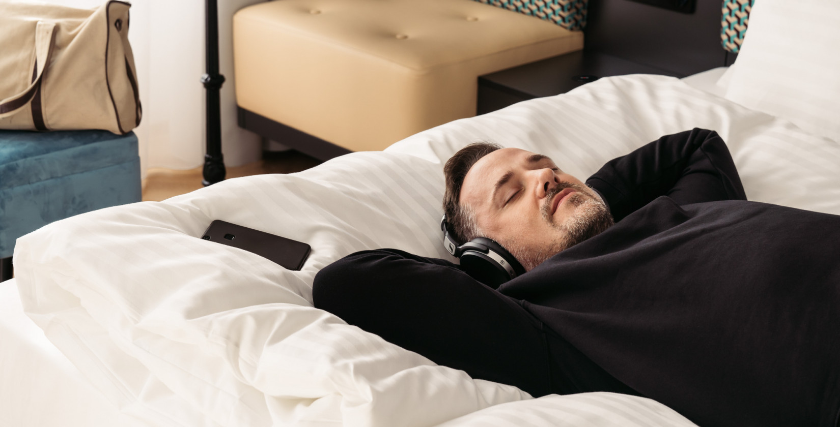 A man lying in bed and listening to music